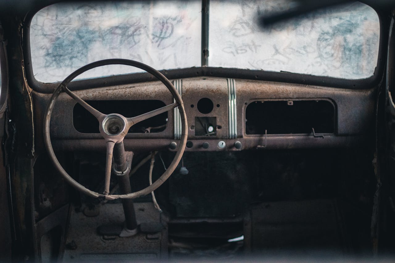 An old car interior with a steering wheel and dashboard